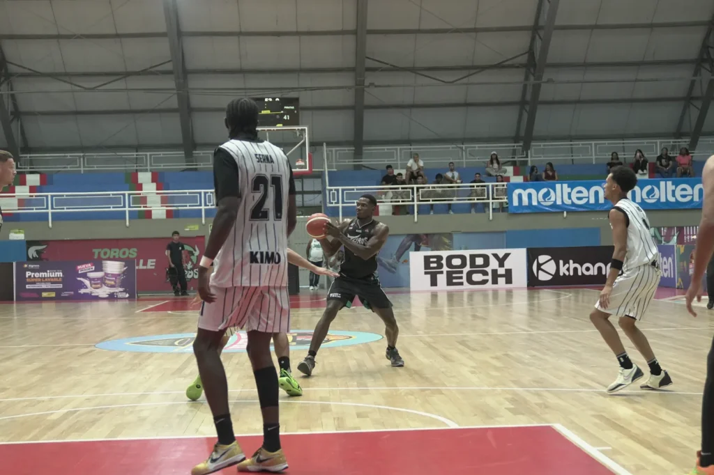 Jugador de Toros del Valle con el balón entre dos defensores de Piratas