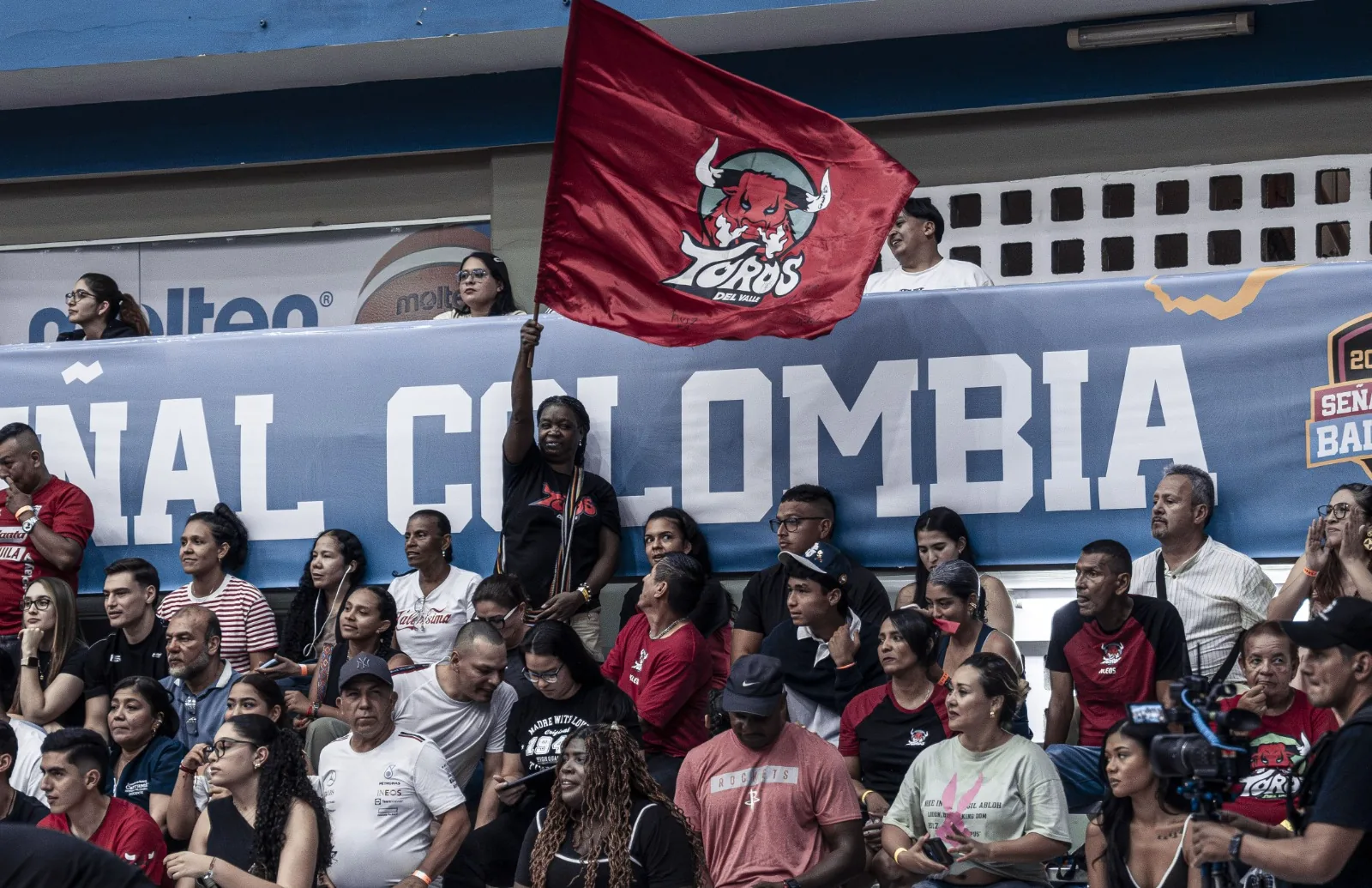 Hincha de Toros del Valle ondea una bandera roja con el escudo del club en las tribunas del Coliseo Evangelista Mora