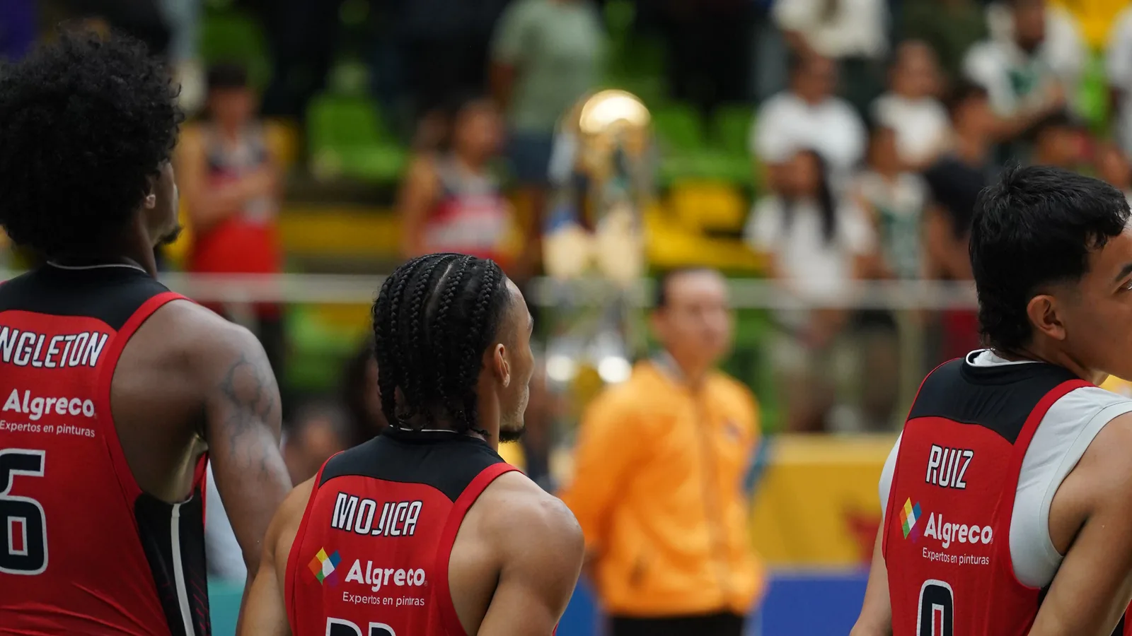 Jugadores de Toros del Valle (Singleton, Mojica y Ruiz) observan el trofeo de campeón de la Liga Señal Colombia de Baloncesto 2026-1