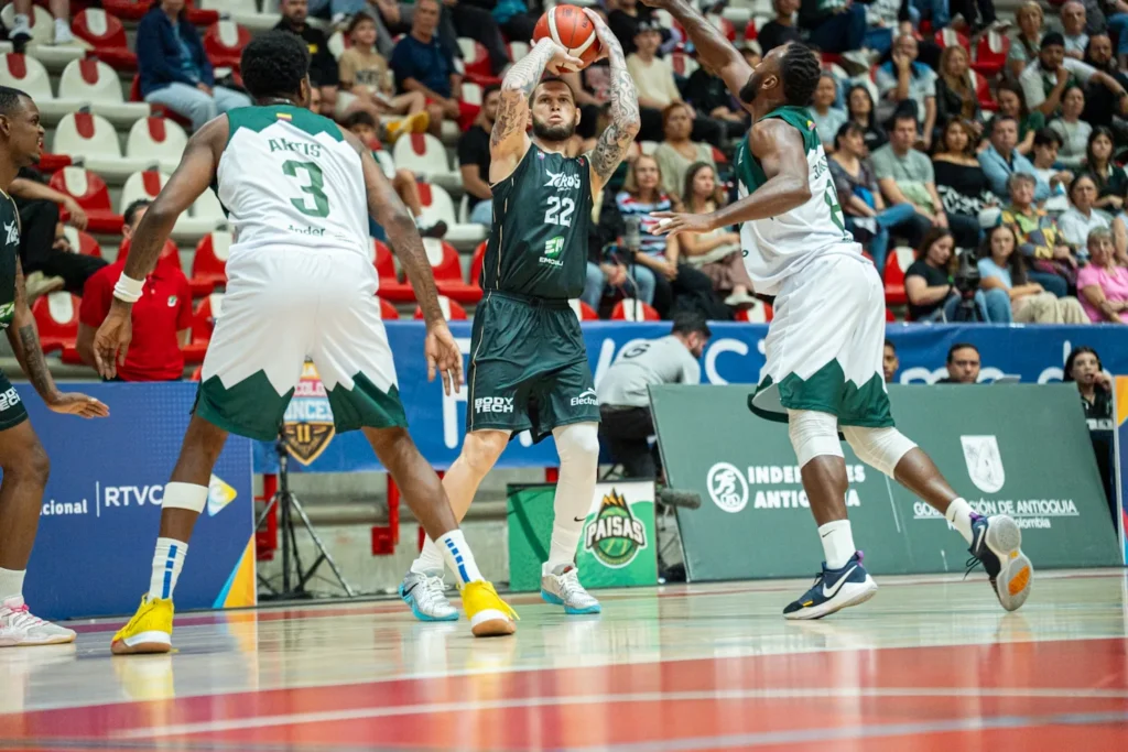 Benito Santiago JR, #22 de Toros del Valle, lanza ante la defensa de dos jugadores de Paisas Basketball