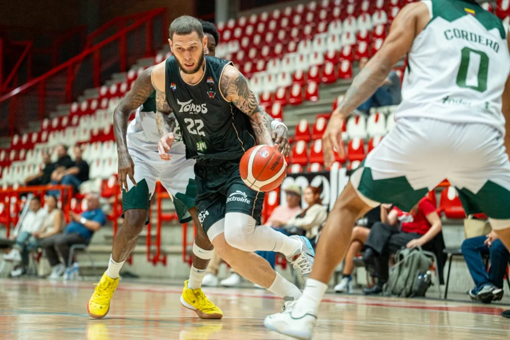 Benito Santiago JR, #22 de Toros del Valle, penetra con el balón ante la defensa de Paisas Basketball