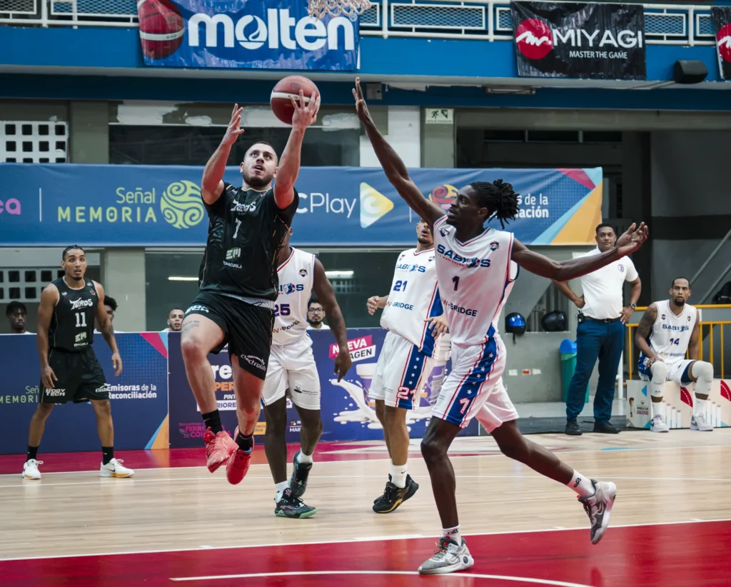 Darwin Blanco (#7) de Toros del Valle se eleva para anotar una bandeja ante la defensa de Sabios de Manizales