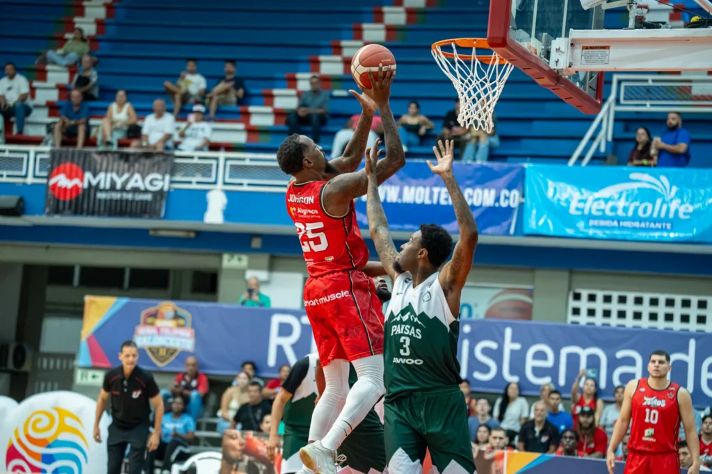 Roquez Johnson, #25 de Toros del Valle, salta y lanza al aro con un defensor de Paisas marcándolo