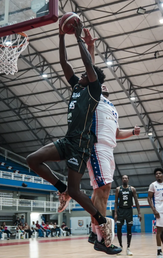 Roquez Johnson (#25) de Toros del Valle salta con el balón hacia el aro ante la defensa de Sabios de Manizales