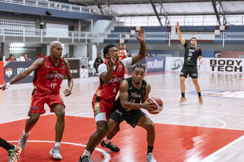 Samuel Mojica protege el balón en una penetración ante dos defensores de Caribbean Storm