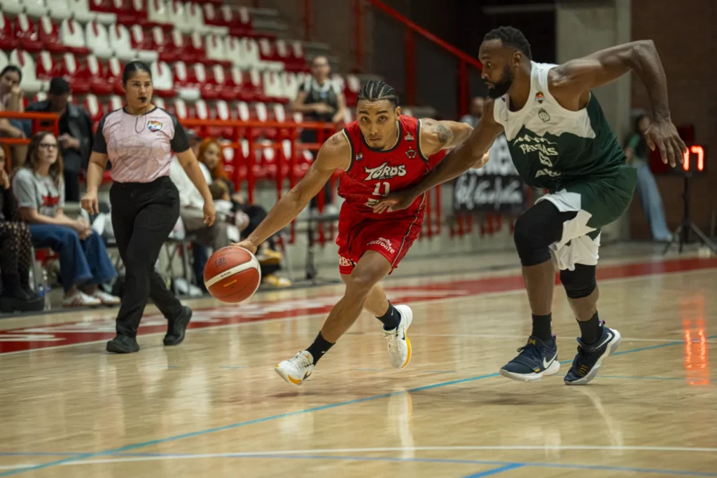 Samuel Mojica penetra con el balón superando a un defensor de Paisas Basketball
