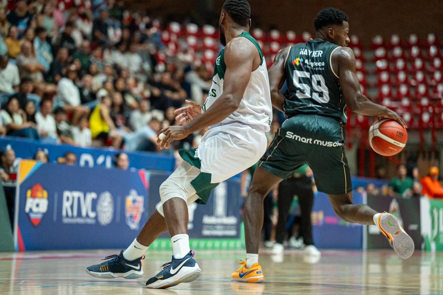Hayner Montaño, #59 de Toros del Valle, avanza con el balón ante la defensa de Paisas Basketball