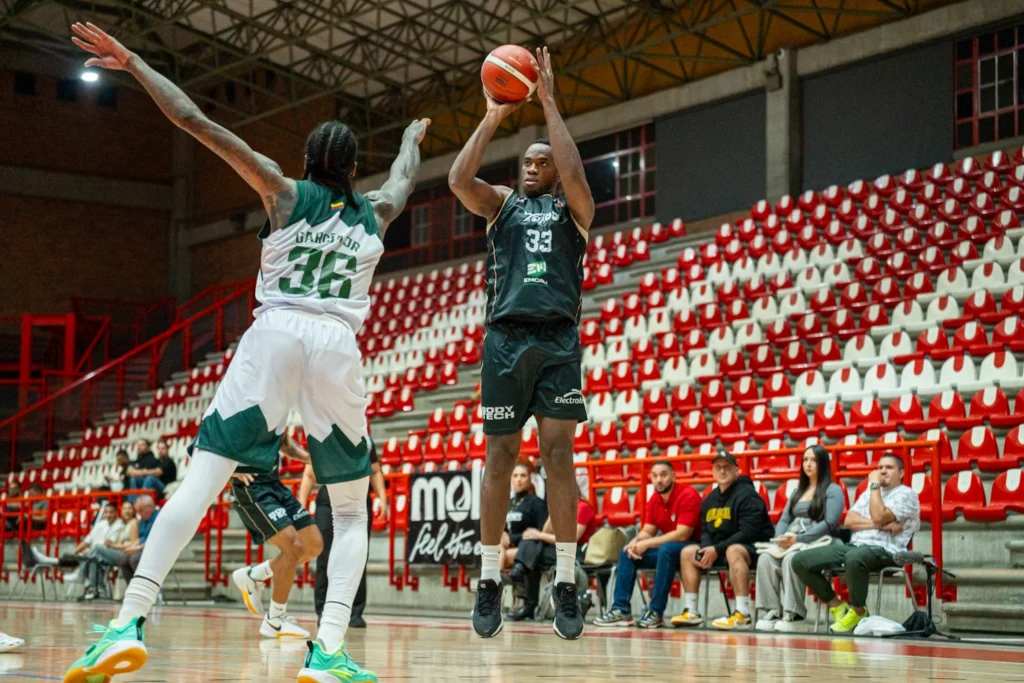 Kevin Quiñones, #33 de Toros del Valle, lanza sobre la marca de un jugador de Paisas Basketball
