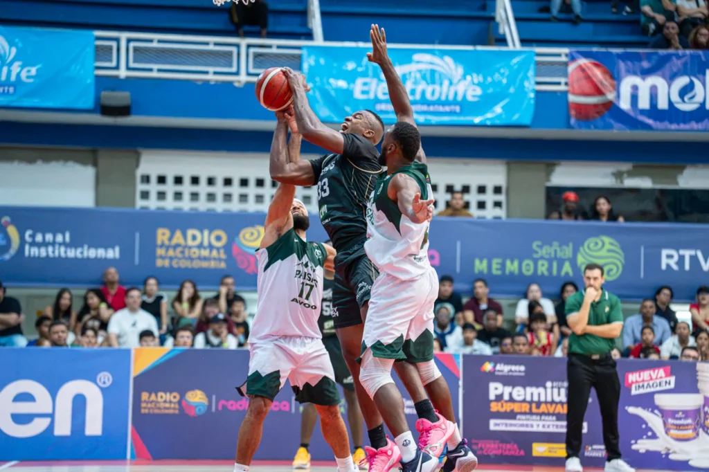 Kevin Qui�ones lanza entre dos defensores de Paisas Basketball en el Evangelista Mora
