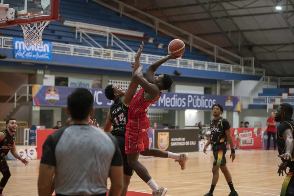 Jugador de Toros del Valle ataca el aro entre dos defensores de Caribbean Storm