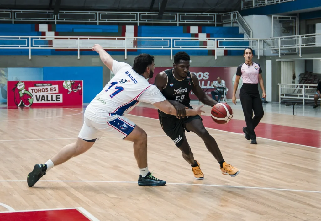 Jugador de Toros del Valle con uniforme negro protege el balón ante la marca de un defensor de Sabios de Manizales