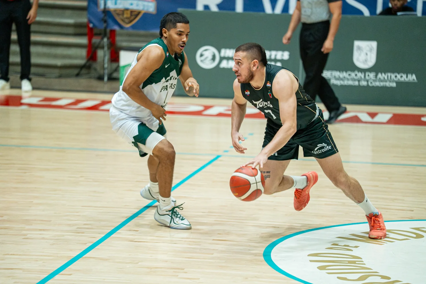 Jugador de Toros del Valle conduce el balón con la defensa de Paisas Basketball encima en Medellín